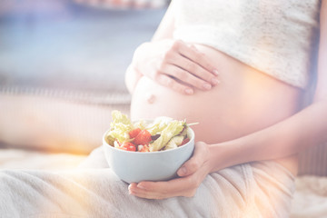 Obraz na płótnie Canvas Pleasant pregnant woman hoding vegetables salad
