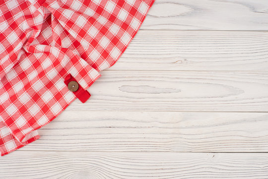Red folded tablecloth over bleached wooden table.