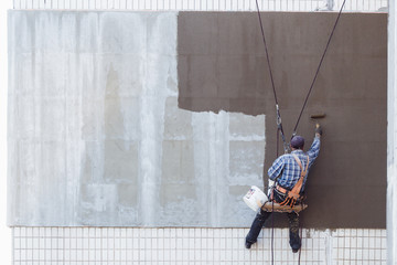 Worker man insulates wall high-rise building © artem_goncharov