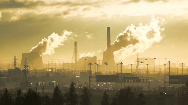 smoked and fogged pipes of factory on the background, the urban river of cars and trees. Original sepia tone as shooted. Saint-Petersburg, Russia. Industrial landscape