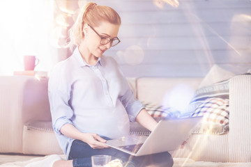 Pleasant pregnant woman using laptop