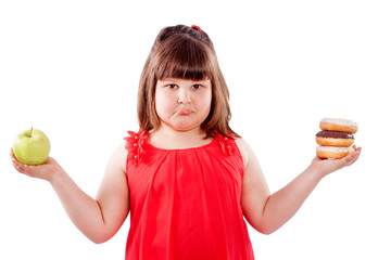 How to teach children to eat healthy food. Girl with food, chooses what to eat donuts or fresh apple, isolated on white background