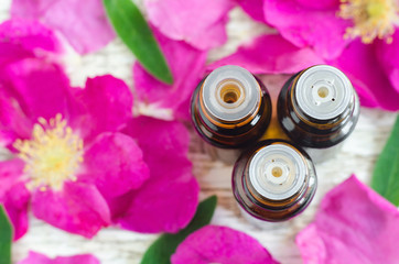 Three small bottles of essential oil and roses petals. Aromatherapy concept. Top view, copy space. 