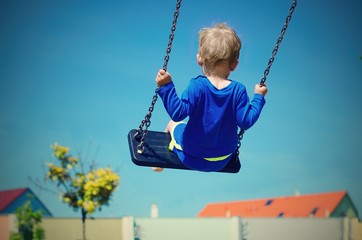 Toddler swinging over the roofs of the houses. Retro colors. Child concept.