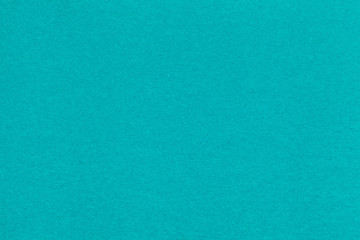 Texture of old turquoise paper closeup. Structure of a dense cardboard. The blue background.