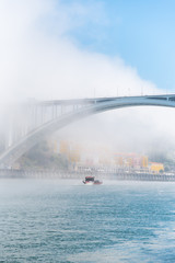 Obraz premium Porto in Portugal, Arrabida bridge, view of the Douro river in the mist, with a traditional boat 