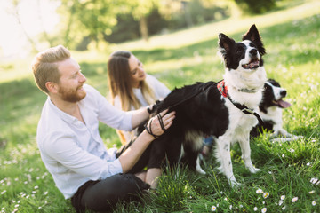 Romantic couple in love walking dogs in nature and smiling