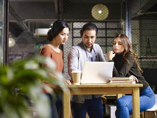 Colleagues working together in an office using a laptop computer