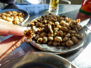 Hand holding a cooked snail - plate with snails in the background