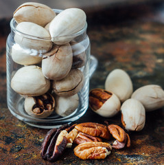 Pecan nuts inside glass jar on rustic surface.