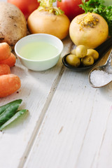 Vegetables, olives and spices over white wooden table.