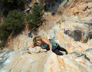 Female Rock Climber makes difficult move vertical Wall top View