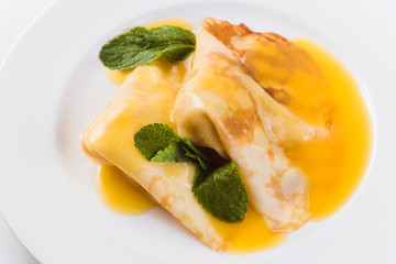 Two pancakes with honey on a white plate on a light background