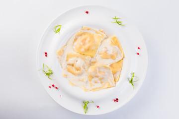 Ravioli stuffed on a white plate on a light background (close)