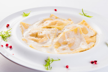 Ravioli stuffed on a white plate on a light background (close)
