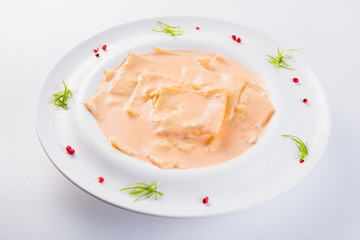 Ravioli stuffed on a white plate on a light background (close)
