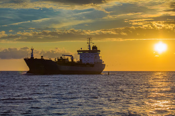 freight ship on sunset light going to port