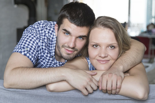 Portrait of smiling young couple at sofa in the living room