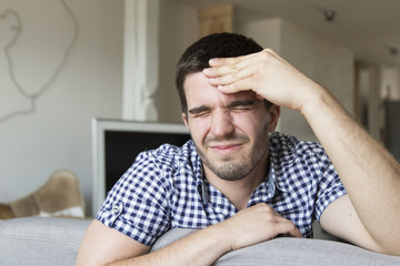 Young man having hard headache at home