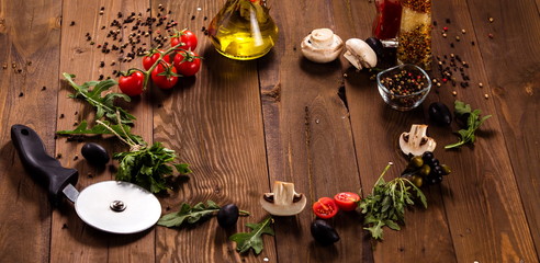 Ingredients for pizza lie in a circle on a dark wooden table