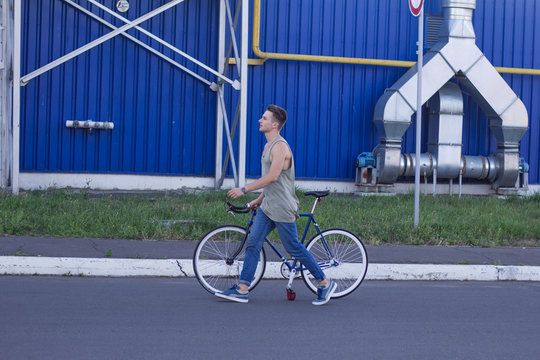Young ,man walk with fixie bike, urban background, picture of hipster with bicycle in blue colors 