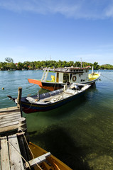 Fototapeta na wymiar traditional malaysian fisherman boat moored, wooden jetty and blue sky background at sunny day
