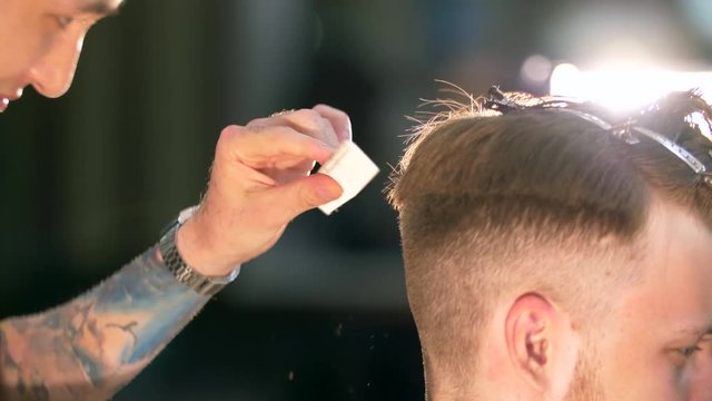 Professional tattooed barber giving a new haircut to his client in a barbershop