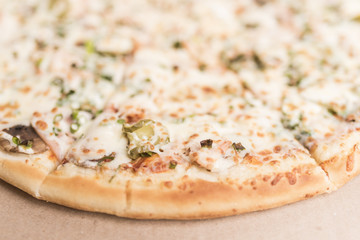 Pizza with mushrooms, ham and pickled cucumbers close-up