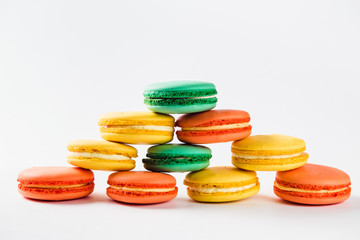 Multicolored macaroons (orange, yellow and green) close.