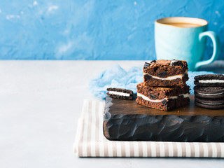 Cream cheese chocolate layer brownies with cookies on wooden serving board