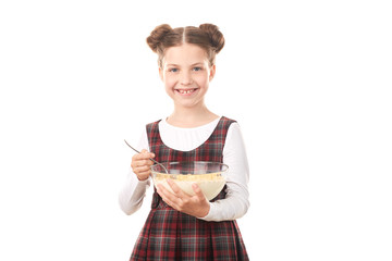 Portrait of cute girl in school uniform eating cereal with milk against white background