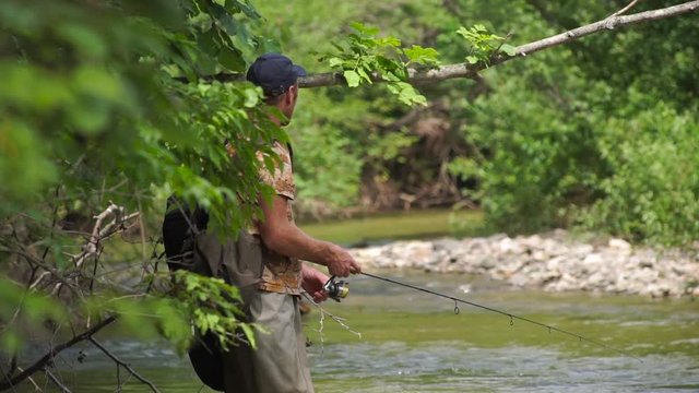Slowmotion shot of a man fishing on a mountain river with a short ultralight spinning using fishing wobblers