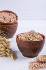Wheat, Oat bran in clay  bowl and ears of wheat and oat.  Dietary supplement to improve digestion. On white background