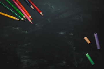 Top view / Flat lay the color pencil and colorful chalk board on black table wooden background.