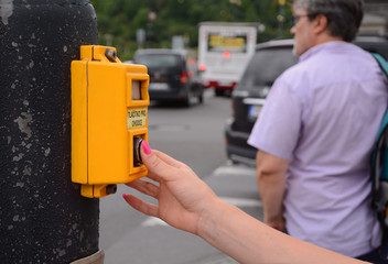 Female hand pressing a button at traffic lights on pedestrian crossing.