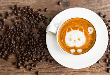 Cat face design of latte art coffee in white cup on wood table with coffee beans around