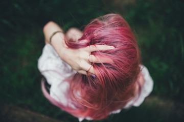 The beautiful girl with pink hair sits on the thrown ladder in an environment of a green grass