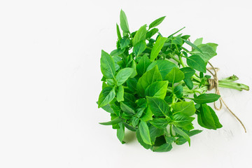 A bunch of green lemon basil on a white concrete table against a brick wall background