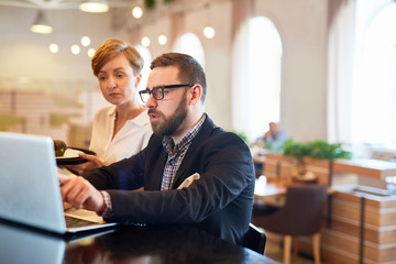 Owner of restaurant explaining changes in online menu to waitress