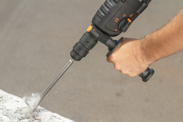 Drill beats concrete with pieces of dust and stone