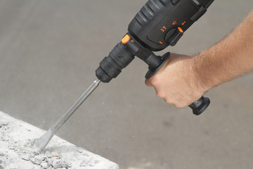 Drill beats concrete with pieces of dust and stone