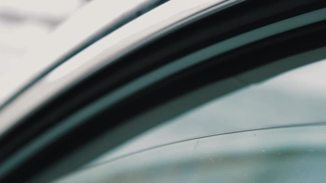 Male hand gives SD memory card to woman driver trough slightly open car window outdoors on cold winter day, close up