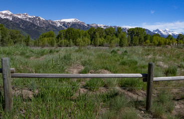 Fototapeta na wymiar Snowcovered mountainrange landscape with split rail wooden fence 