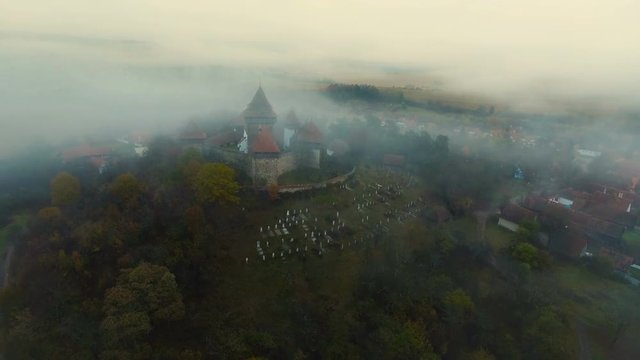 Drone flying backwards from the medieval church from Viscri village.	Countryside view with Viscri fortified church in the middle surrounded by saxon houses. Transylvania, Romania. 4k footage.
