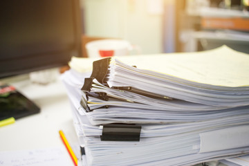 Stack of papers files on work desk in office, business report paper or piles of unfinished...