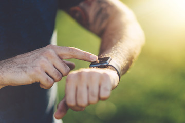 Close up shot of young sportsman using smartwatch to track him workout performance