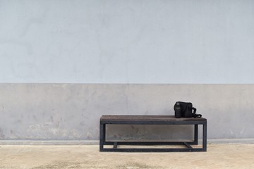 lens and camera bag on steel long bench in front of dirty gray old wall for waiting to work in...