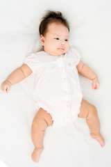 Portrait of a little adorable infant baby girl lying on back on the blanket