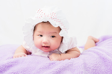 Portrait of a little adorable infant baby girl lying on the tummy on the pillow with head band