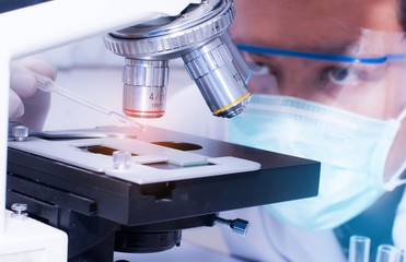 Scientist droping liquid to the slide with microscope in laboratory room. Scientific research